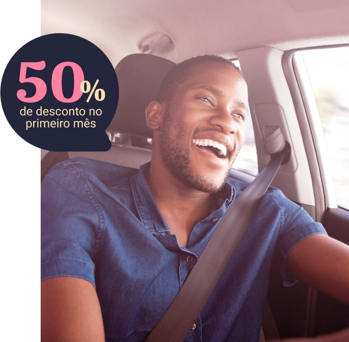 Imagem frontal de um homem dirigindo um carro olhando para a estrada e sorrindo, um balão de fala na parte superior do lado esquerdo de 50% de desconto no primeiro mês