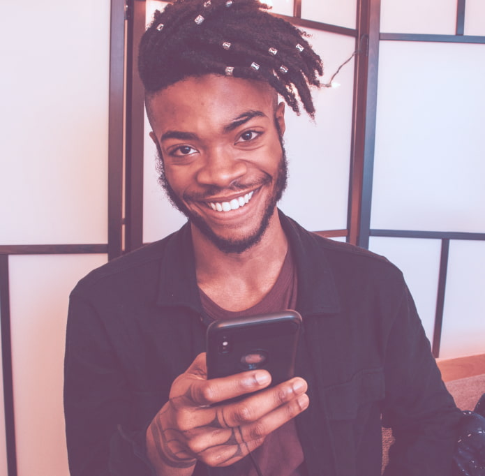 Homem jovem sorrindo segurando um smartphone, um balão de fala na parte superior do lado esquerdo de 50% de desconto no primeiro mês
